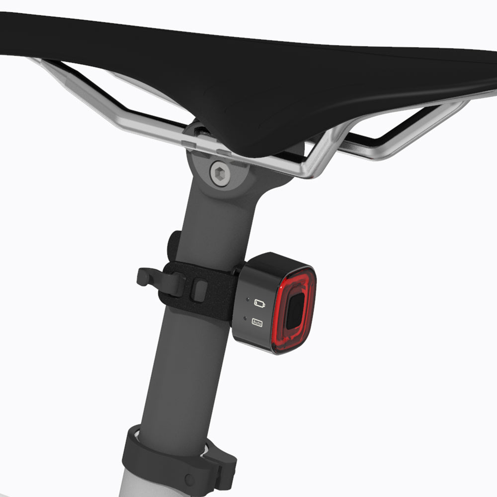 Bicycle seat with a black and red light attached on a white background