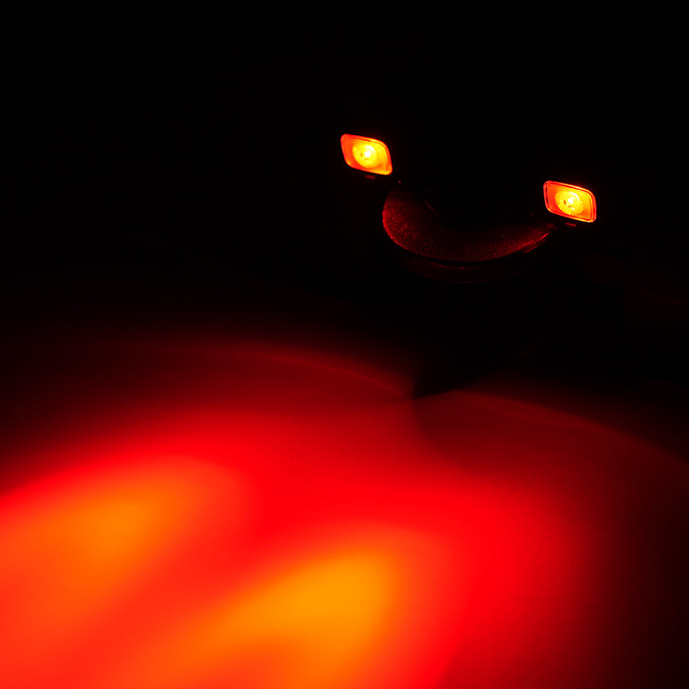 Close-up of a car's red and orange brake lights on a black background