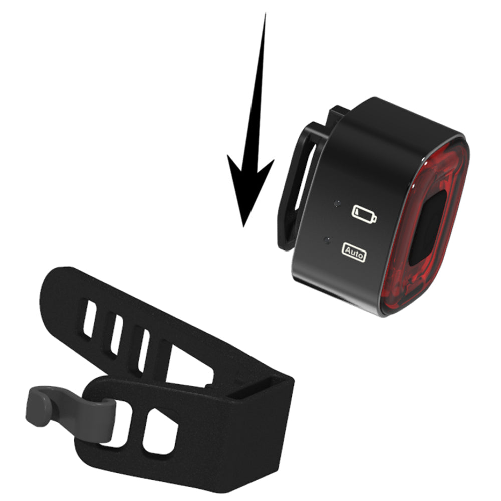 Black bike light with red lens and mounting bracket on a white background
