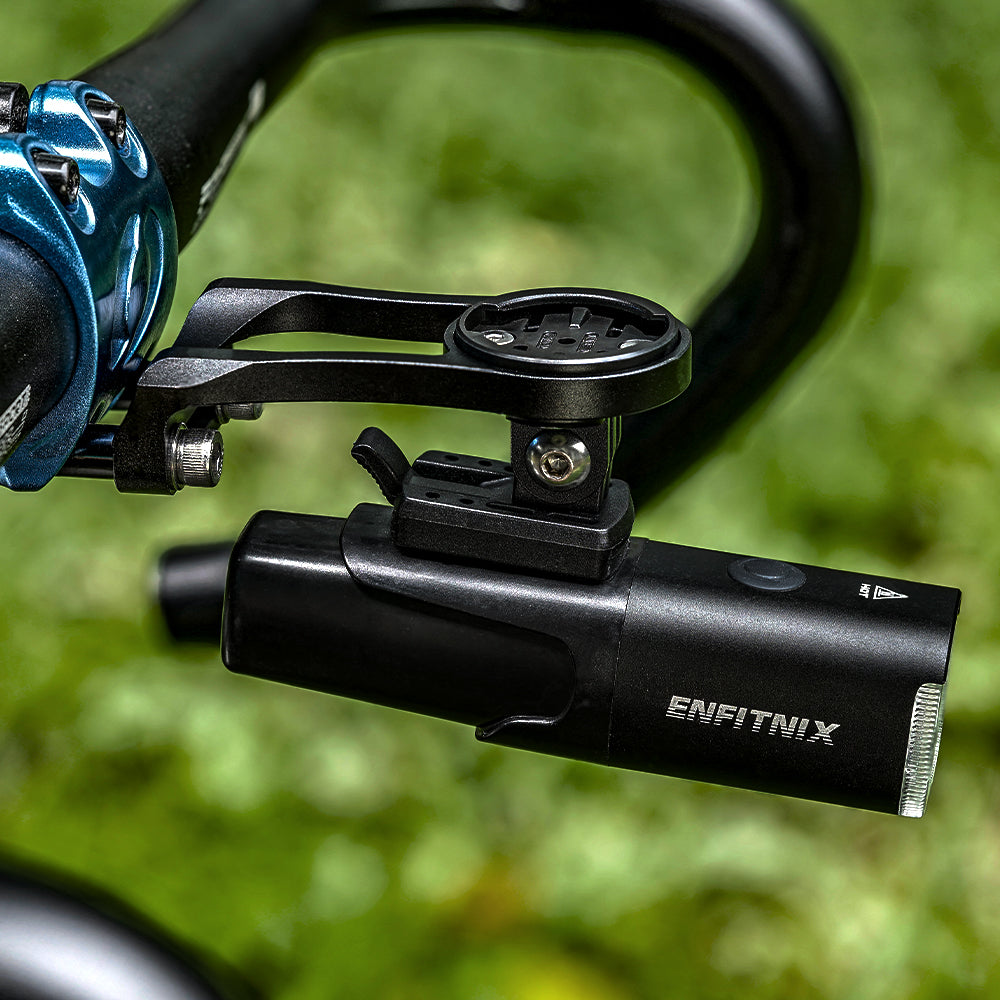 Black Enfitnix bike light attached to a bicycle handlebar with a blurred green background