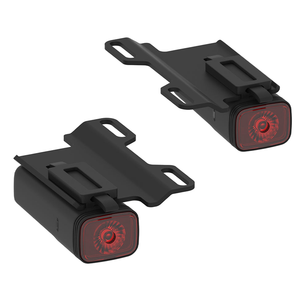Two black bike lights with red lenses on a white background