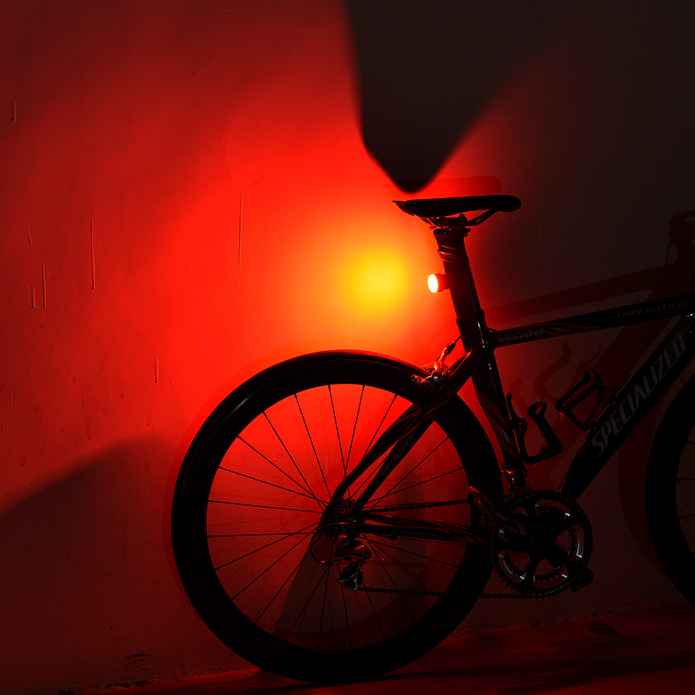 Silhouette of a bicycle against a red wall with a light source.