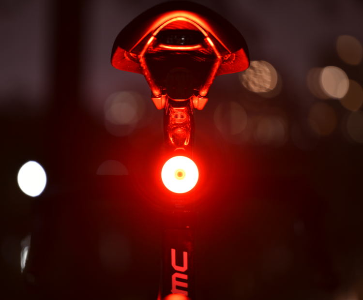 A xlitese bicycle taillight tied to the bicycle seat pole emits a bright red light in the dark